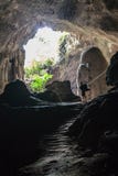 Cave with man standing on a rock in front of the entrance stock images Cave with man standing on a rock in front of the entrance stock images