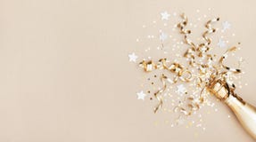 Celebration background with golden champagne bottle, confetti stars and party streamers. Christmas, birthday or wedding. Flat lay