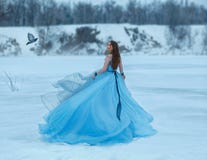 Cendrillon dans une robe luxueuse, luxuriante, bleue avec un train magnifique Une fille marche sur un lac congelé couvert de neig photographie stock Cendrillon dans une robe luxueuse, luxuriante, bleue avec un train magnifique Une fille marche sur un lac congelé couvert de neig photographie stock
