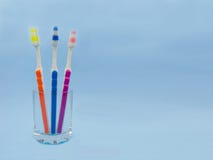 Cepillos de dientes en un vidrio, fondo azul Copie el espacio imagen de archivo Cepillos de dientes en un vidrio, fondo azul Copie el espacio imagen de archivo