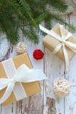 Cerca - para arriba de las cajas de regalo con la cinta blanca en el fondo blanco texturizado de madera rodeado por las ramas y l fotos de archivo Cerca - para arriba de las cajas de regalo con la cinta blanca en el fondo blanco texturizado de madera rodeado por las ramas y l fotos de archivo