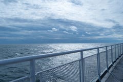 Cercando con barandilla en la cubierta superior de una nave, convergiendo con el horizonte y el cielo azul imponente en la distan fotografía de archivo Cercando con barandilla en la cubierta superior de una nave, convergiendo con el horizonte y el cielo azul imponente en la distan fotografía de archivo