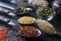 Cereais, sementes e feijões orgânicos crus em colheres e em umas bacias de madeira Imagem de Stock Cereais, sementes e feijões orgânicos crus em colheres e em umas bacias de madeira Imagem de Stock