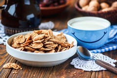 Cereal in white ceramic bowl with spoon on wooden table. Multigrain flakes and cup of milk with smile. royalty free stock photos Cereal in white ceramic bowl with spoon on wooden table. Multigrain flakes and cup of milk with smile. royalty free stock photos