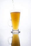 Cerveja não filtrada clara derramada em uma caneca cozinhando em um fundo branco com reflexão foto de stock royalty free Cerveja não filtrada clara derramada em uma caneca cozinhando em um fundo branco com reflexão foto de stock royalty free