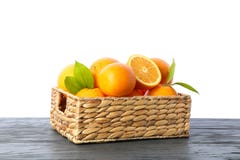Cesta de vime com as laranjas maduras na tabela de madeira isolada no fundo branco imagens de stock Cesta de vime com as laranjas maduras na tabela de madeira isolada no fundo branco imagens de stock