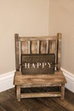 Chaise en bois rustique de petits childs se reposant dans le coin d'une salle avec le signe en bois qui indique HEUREUX là-dessus images libres de droits Chaise en bois rustique de petits childs se reposant dans le coin d'une salle avec le signe en bois qui indique HEUREUX là-dessus images libres de droits