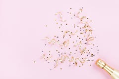 Champagne bottle with confetti stars and party streamers on pink background. Christmas, birthday or wedding concept. Flat lay.