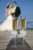 Champagne glasses with bride and groom in background.