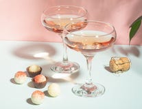 Champagne ou vin en divers chocolats en verre élégants du chocolat blanc sur une lumière dure de fond de rose Copiez l'espace image stock Champagne ou vin en divers chocolats en verre élégants du chocolat blanc sur une lumière dure de fond de rose Copiez l'espace image stock