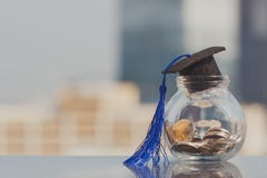 Chapeau d'obtention du diplôme sur l'argent de pièces de monnaie dans la bouteille en verre sur le fond blanc photos stock Chapeau d'obtention du diplôme sur l'argent de pièces de monnaie dans la bouteille en verre sur le fond blanc photos stock