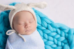 Chapeau de port adorable d'oreilles de lapin d'enfant nouveau-né dormant sur un lit image stock Chapeau de port adorable d'oreilles de lapin d'enfant nouveau-né dormant sur un lit image stock
