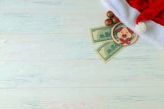 Chapeau de Santa Claus, 100 billets d'un dollar, un jouet porcin, un symbole de 2019, et jouets de Noël sur un fond clair en bois image libre de droits Chapeau de Santa Claus, 100 billets d'un dollar, un jouet porcin, un symbole de 2019, et jouets de Noël sur un fond clair en bois image libre de droits