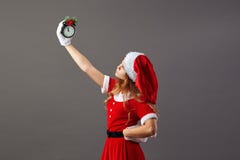 Charmante Mevr. Santa Claus gekleed in de de rode robe, hoed van de Kerstman en de witte handschoenen houdt een klok die vijf aan stock foto Charmante Mevr. Santa Claus gekleed in de de rode robe, hoed van de Kerstman en de witte handschoenen houdt een klok die vijf aan stock foto