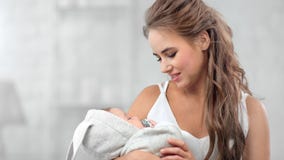 Charming happy young mother lulling newborn baby feeling togetherness and positive emotion