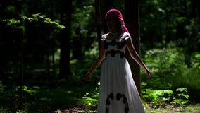 Charming lady dressed long gown and ethnic headscarf is walking in forest at summer morning