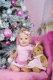 Charming little girl with blue eyes sitting in a pink armchair teddy bear on background decorated Christmas tree stock photography Charming little girl with blue eyes sitting in a pink armchair teddy bear on background decorated Christmas tree stock photography