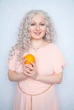 Charming plump curly blonde in pink dress with orange on white solid studio background alone stock photos Charming plump curly blonde in pink dress with orange on white solid studio background alone stock photos