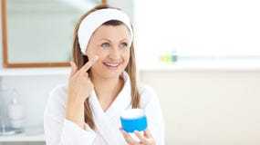 Charming young woman using cream in the bathroom stock photography Charming young woman using cream in the bathroom stock photography