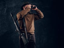 Chasseur avec le fusil de chasse observant par des jumelles Photo de studio sur le fond fonc? de mur image libre de droits Chasseur avec le fusil de chasse observant par des jumelles Photo de studio sur le fond fonc? de mur image libre de droits