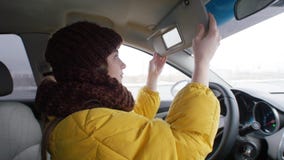 Chaufför för ung kvinna som sitter i bilen och ser på spegeln royaltyfri fotografi Chaufför för ung kvinna som sitter i bilen och ser på spegeln royaltyfri fotografi