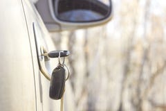 Chaves esquecidas do carro na porta, um fundo de uma floresta obscura do outono com um efeito do bokeh foto de stock Chaves esquecidas do carro na porta, um fundo de uma floresta obscura do outono com um efeito do bokeh foto de stock