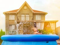 Cheerful child playing in water. Water pool on front, back yard. Children and nature. Summer time. Traveling concept