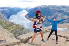A cheerful couple and their little kid in the summit of the Pulpit Rock Preikestolen, Norway. royalty free stock image A cheerful couple and their little kid in the summit of the Pulpit Rock Preikestolen, Norway. royalty free stock image