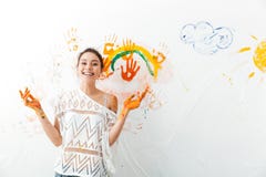 Cheerful cute young woman painting on white wall by hands stock photos Cheerful cute young woman painting on white wall by hands stock photos