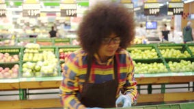 Cheerful energetic supermarket employee african american woman with an afro hairstyle sorts the fruit stock video Cheerful energetic supermarket employee african american woman with an afro hairstyle sorts the fruit stock video
