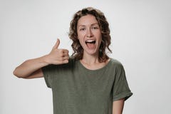 Cheerful enthusiastic young curly woman with opens eyes and mouth widely showing stock photos Cheerful enthusiastic young curly woman with opens eyes and mouth widely showing stock photos