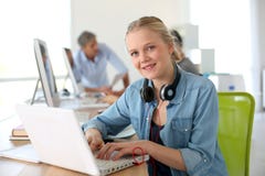 Cheerful girl in computing class using laptop royalty free stock images Cheerful girl in computing class using laptop royalty free stock images