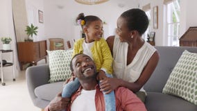 Little black girl playing with parents at home