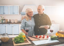 Cheerful married senior couple cooking in kitchen with enjoyment stock image Cheerful married senior couple cooking in kitchen with enjoyment stock image