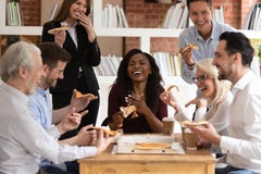 Cheerful multiracial office business people laugh share takeaway pizza together