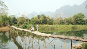 Cheerful Tourist crossing bamboo bridge motorbike, limestone view, laos stock photos Cheerful Tourist crossing bamboo bridge motorbike, limestone view, laos stock photos