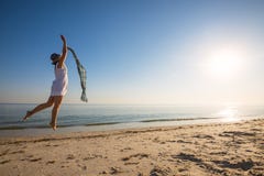 Cheerful Woman, With A Scarf, Jumps On The Beach Stock Images Cheerful Woman, With A Scarf, Jumps On The Beach Stock Images