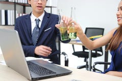 Cheerful young Asian business partners clinking bottle of wine in office. Successful and celebration concept. Stock Photos Cheerful young Asian business partners clinking bottle of wine in office. Successful and celebration concept. Stock Photos