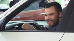Cheerful young handsome man smiling to the camera sitting in his new car royalty free stock photography Cheerful young handsome man smiling to the camera sitting in his new car royalty free stock photography
