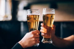 Cheers. Close-up of two men in shirts toasting with beer at the bar counter Stock Photo Cheers. Close-up of two men in shirts toasting with beer at the bar counter Stock Photo