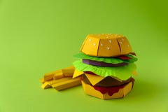 Cheeseburger de papier avec du boeuf, le fromage, la tomate, la laitue, l'oignon, le lard et les fritures sur le fond vert Copiez photos stock Cheeseburger de papier avec du boeuf, le fromage, la tomate, la laitue, l'oignon, le lard et les fritures sur le fond vert Copiez photos stock