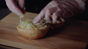 Chef, der Burger macht das Brötchen auf dem Grill braten, den Kopfsalat setzend stock footage Chef, der Burger macht das Brötchen auf dem Grill braten, den Kopfsalat setzend stock footage
