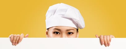 Chef féminin asiatique tenant l'affiche pour le texte image libre de droits Chef féminin asiatique tenant l'affiche pour le texte image libre de droits