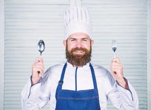 Chef happy smiling face hold spoon and fork. Man handsome with beard holds kitchenware on white background. Cooking stock photography Chef happy smiling face hold spoon and fork. Man handsome with beard holds kitchenware on white background. Cooking stock photography