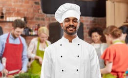 Chef indien masculin heureux dans la toque au cours de cuisine photographie stock Chef indien masculin heureux dans la toque au cours de cuisine photographie stock