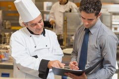 Chef principal et serveur discutant le menu image stock Chef principal et serveur discutant le menu image stock