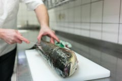 Chef in restaurant kitchen filleting carp fish