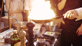 Chef`s Masterclass. Chef Cooking With Fire In Frying Pan.nProfessional Chef In a Commercial Kitchen Cooking Flambe Style