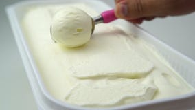 Chef scooping vanilla ice cream out of container
