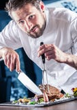 chef Szef kuchni z nożem i rozwidleniem Fachowy szef kuchni w hotelu lub restauraci przygotowywa up kość stek lub ciie Szefa kuch obraz royalty free chef Szef kuchni z nożem i rozwidleniem Fachowy szef kuchni w hotelu lub restauraci przygotowywa up kość stek lub ciie Szefa kuch obraz royalty free